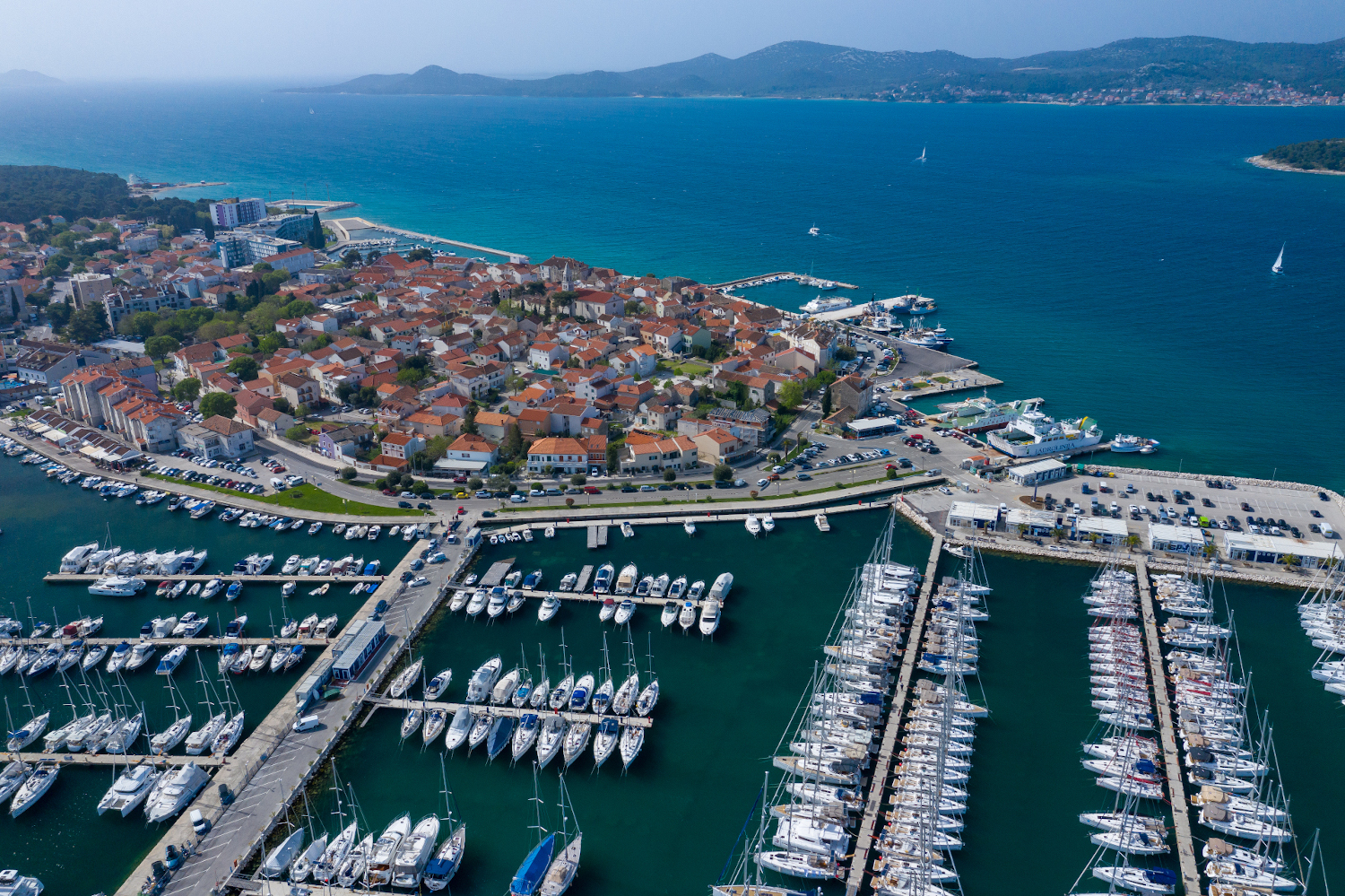 Aerial View of Yacht Club and Marina in Biograd na Moru. Summer time in Dalmatia region of Croatia. Coastline and turquoise water and blue sky. Photo made by drone from above.